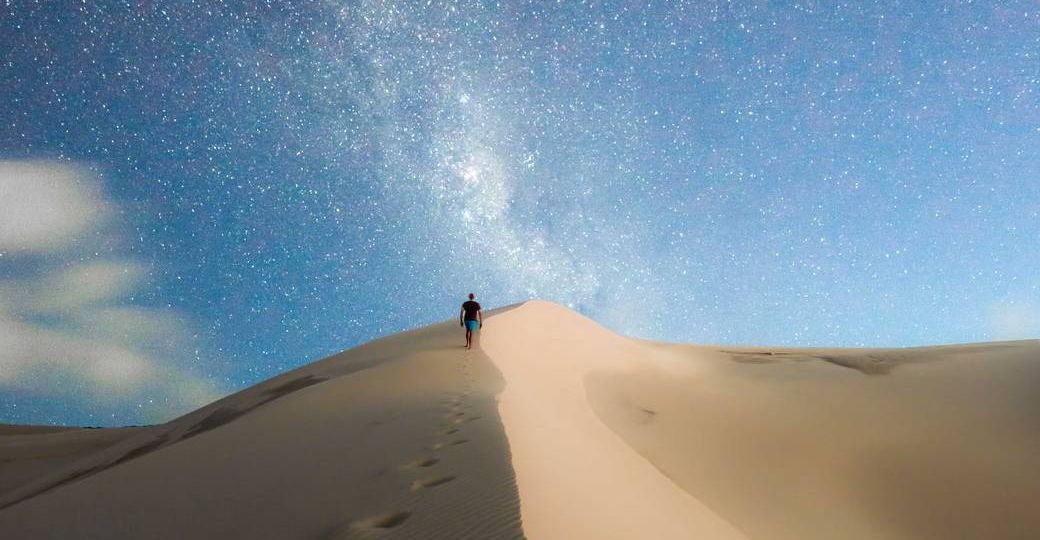 photo of person walking on desert during evening